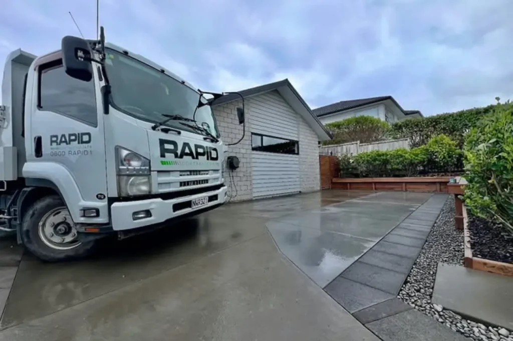 Backed By Proven Experience In Asphalt Construction Asphalt Contractors Auckland featuring a completed residential driveway project with a branded company vehicle on site.
