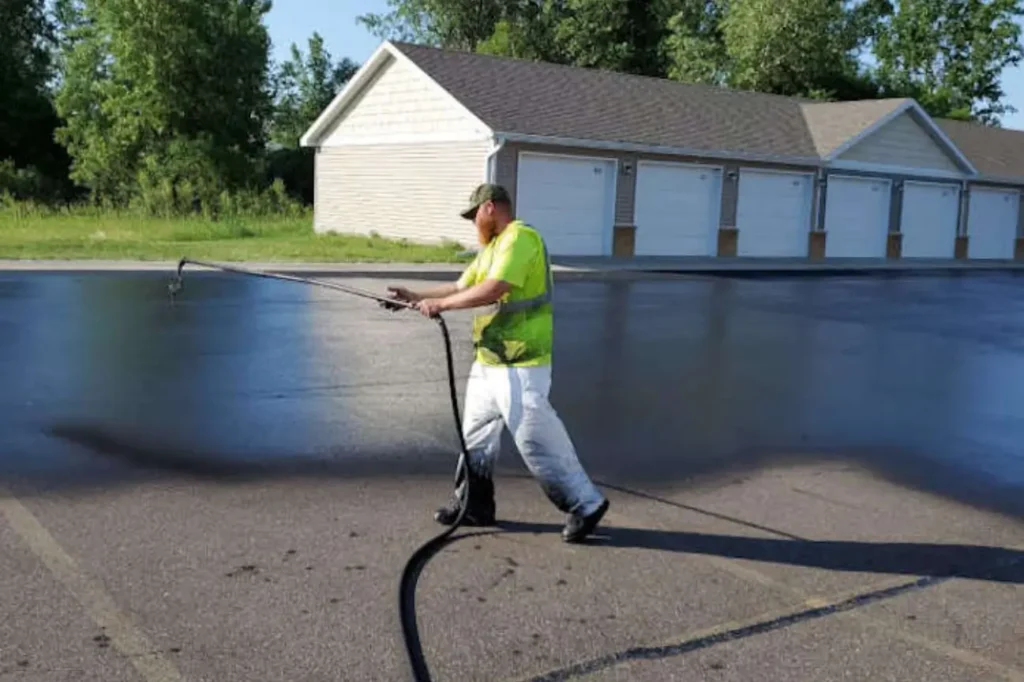 Asphalt Contractors Auckland technician applying Tar Sealing to a large paved area for lasting asphalt protection.