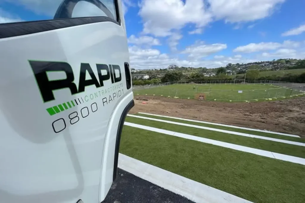 Welcome To Asphalt Contractors Auckland Where Quality Surfaces Begin With Trust showcased on a completed sports field project beside a branded company vehicle.