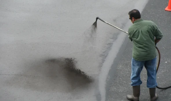 Enhanced Durability and Longevity with Tar Sealing by Asphalt Contractors Auckland Asphalt Contractors Auckland specialist applying Tar Sealing to asphalt surface to improve durability and longevity.